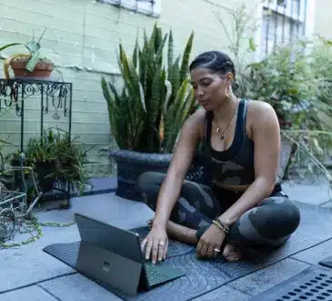 a woman sitting on the ground working on a laptop