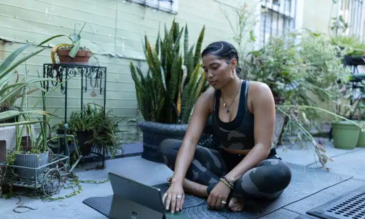 a woman sitting on the ground working on a laptop