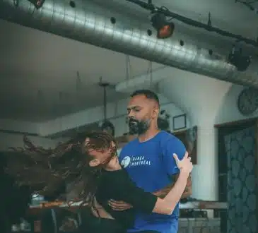 man in blue crew neck t-shirt and blue denim jeans sitting on brown wooden floor