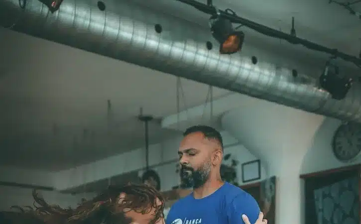 man in blue crew neck t-shirt and blue denim jeans sitting on brown wooden floor